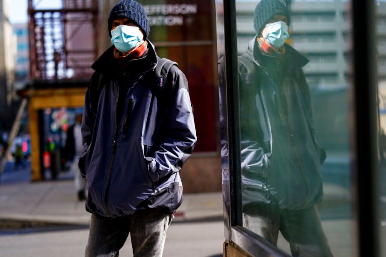 A person wearing a face masks to protect against the spread of the coronavirus walks in Philadelphia.