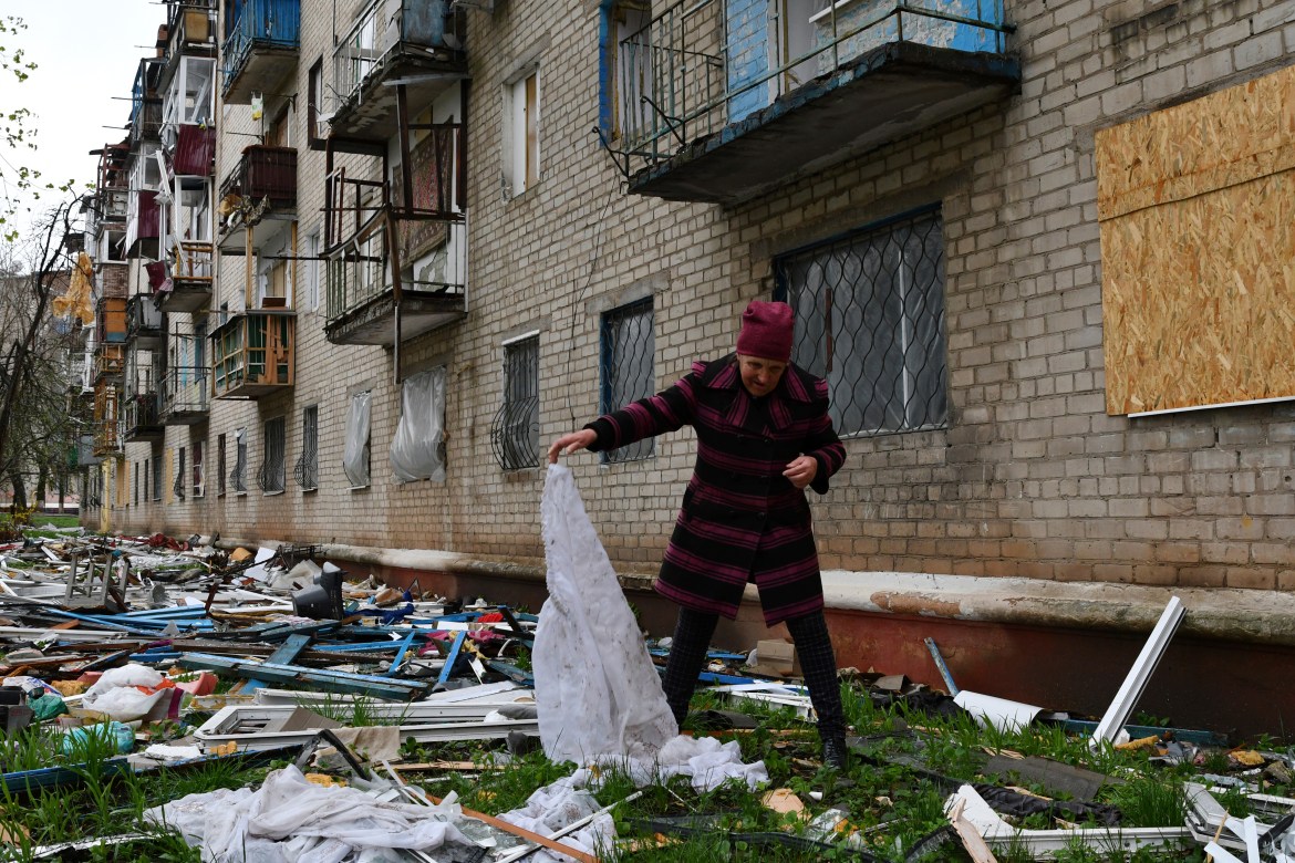 A woman looks for goods dropped from the apartment building partly damaged by shelling, in Kramatorsk