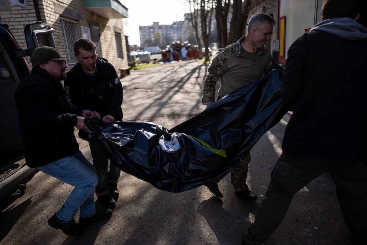 Volunteers carry the body of a man killed during the war to a refrigerated container in Bucha