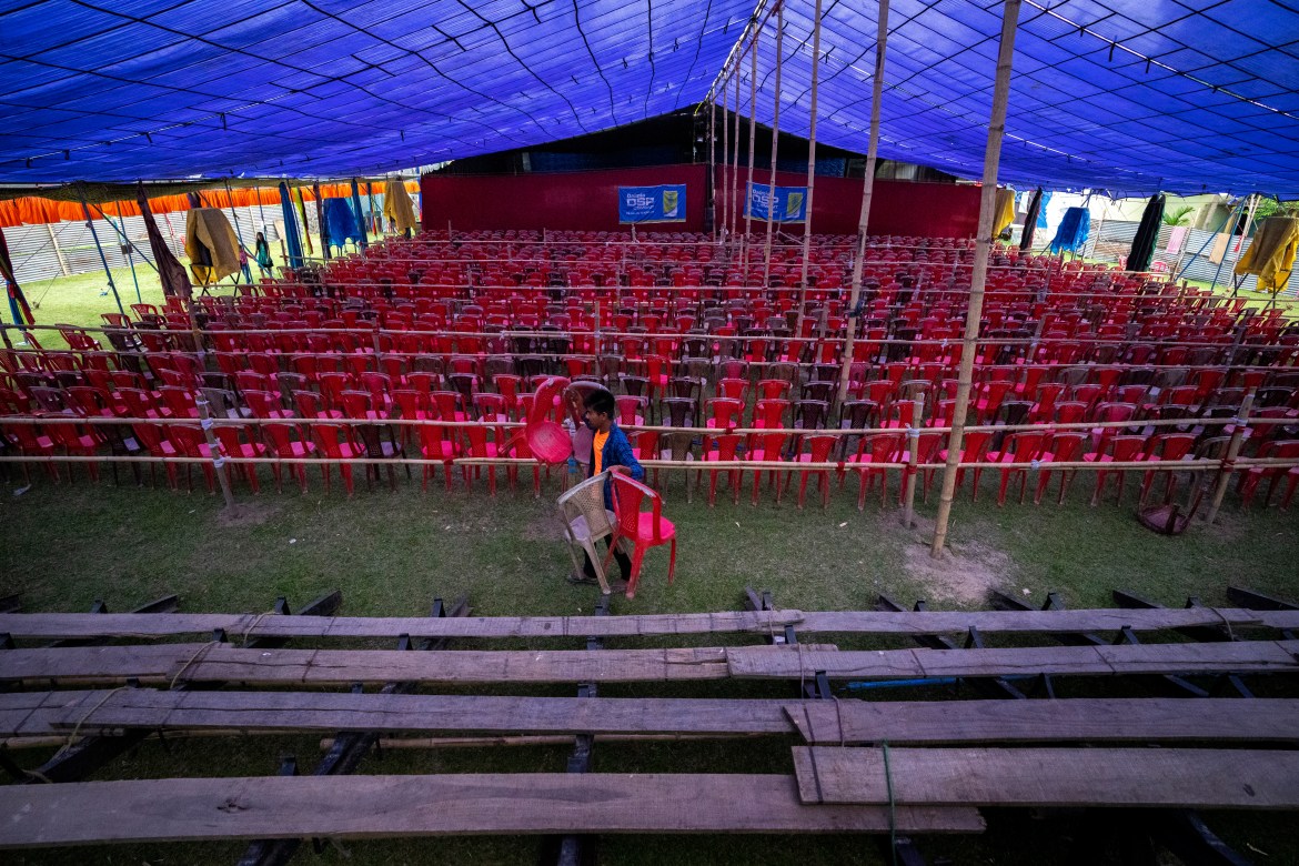 A volunteer arranges chairs inside a tent for a performance by Awahan Theater at Xetali village