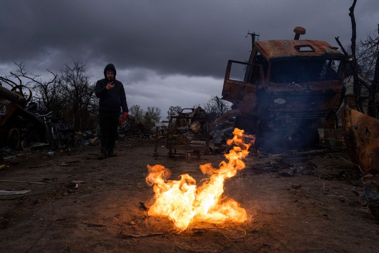 A man takes a photo of burning propellant in a street near destroyed Russian military vehicles near Chernihiv, Ukraine, Sunday, April 17, 2022.