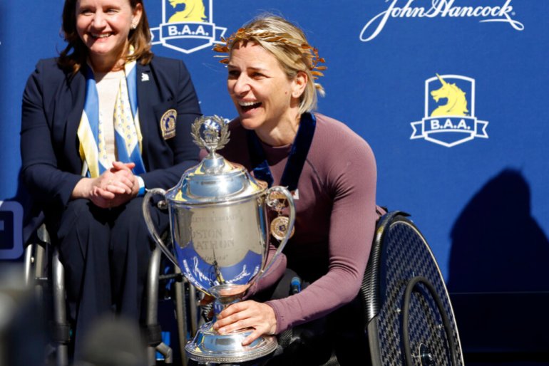 Manuela Schar of Switzerland smiles as she holds the trophy after winning the women's wheelchair division of the 126th Boston Marathon.