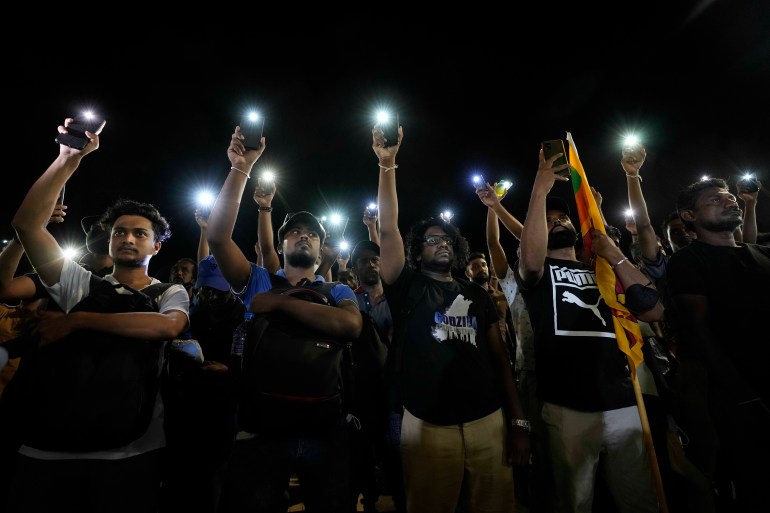 Sri Lankans hold up their mobile phone torches