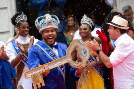 Carnival King Momo, Wilson Dias da Costa Neto, holds the key of the city as Rio de Janeiro Mayor Eduardo Paes, right, applauds during a ceremony in Rio de Janeiro, Brazil.