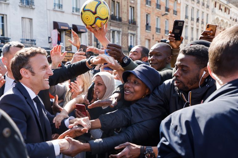 French President Emmanuel Macron holds hands to residents during a campaign stop Thursday, April 21, 2022 in Saint-Denis, outside Paris.