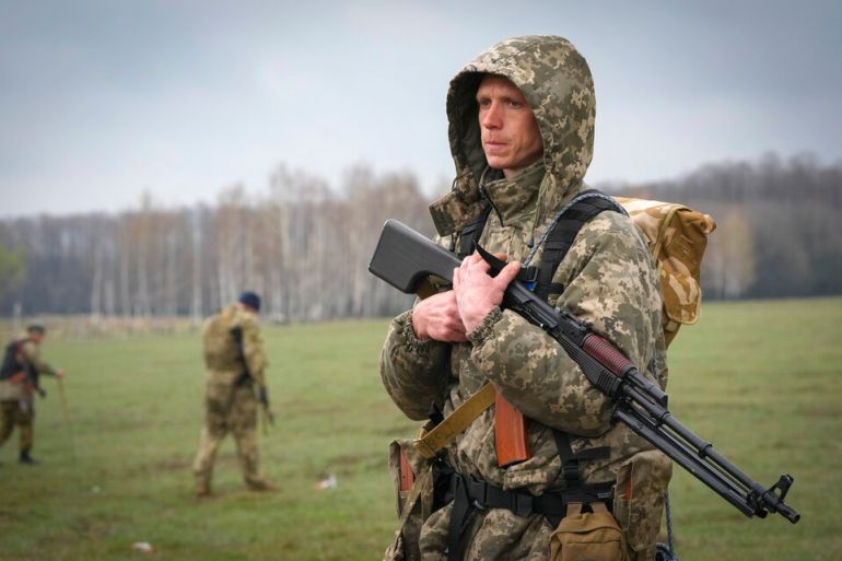 A Ukrainian soldier stands as sappers search for mines left by the Russian troops in fields.