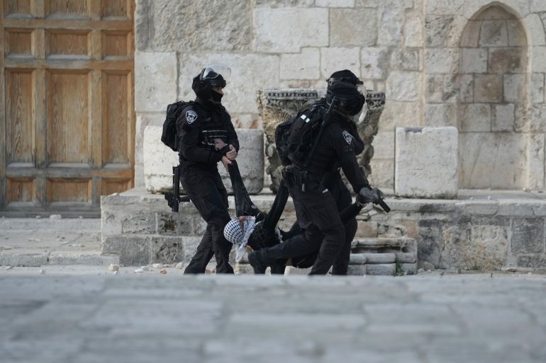 Israeli police carry a Palestinian protester during clashes at the Al Aqsa Mosque compound