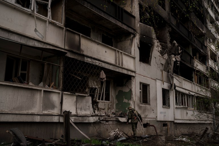 A Ukrainian service member inspects a heavily damaged apartment building after Russian bombardment in Kharkiv, Ukraine.