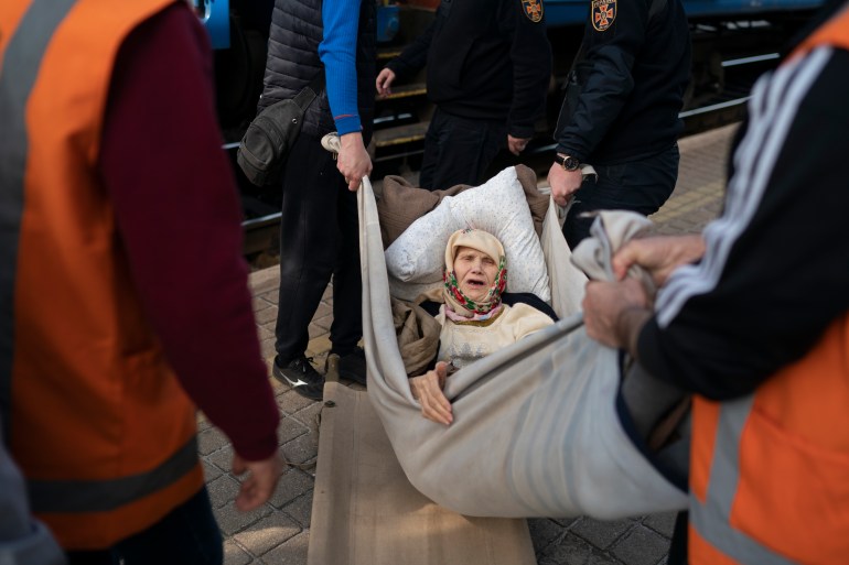 Klavidia, 91, is carried on an improvised stretcher as she boards a train, fleeing the war in Severodonetsk at a train station in Pokrovsk, Ukraine