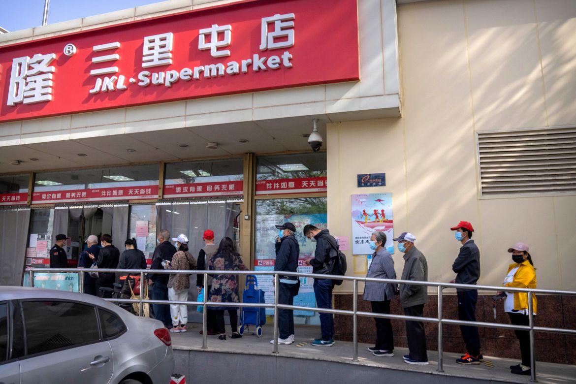People wearing face masks line up outside a supermarket in Beijing