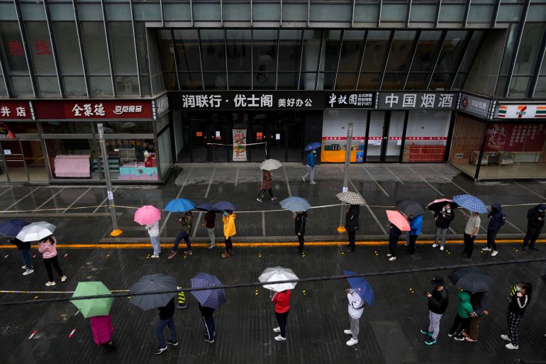 Locked-down residents line up in the rain for COVID test outside shuttered office complex on Wednesday, April 27, 2022, in Beijing.