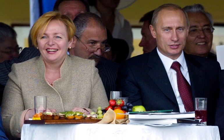 Il presidente Vladimir Putin (seduto a destra, in abito) e la sua allora moglie Lyudmila (in giacca beige e sorridente) guardano le corse di cavalli a Mosca nel 2004