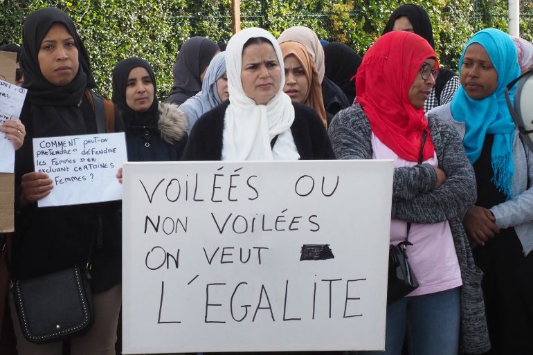 Women wearing headscarves demonstrate and hold placards