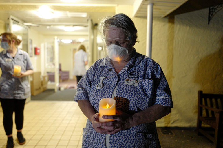 A nurse in uniform seen holding a candle