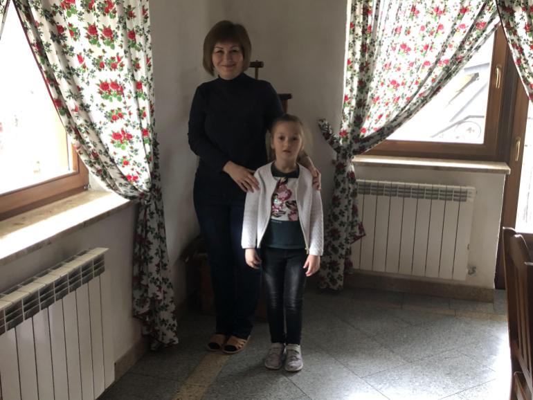 A photo of Iryna Lipsova and Nadiya standing in front of windows with floral curtains.
