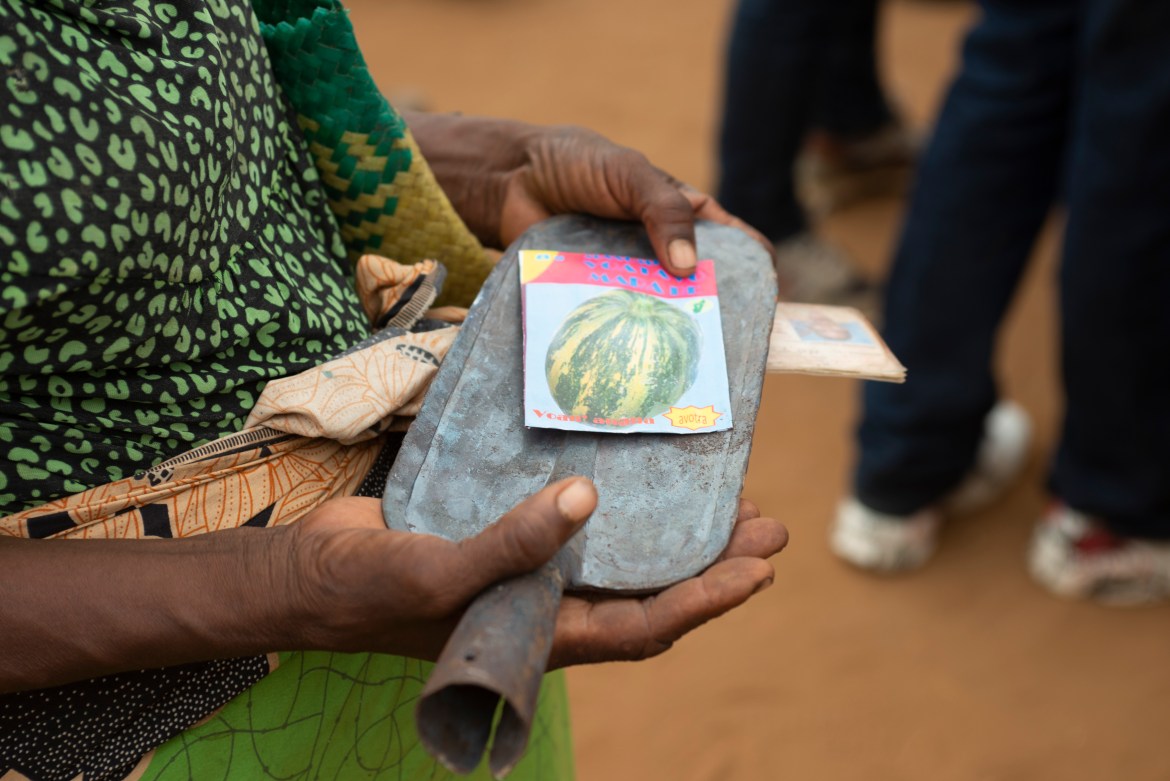 A woman holds a spade and seeds she received at a government aid distribution event in Maraoalomainte village, Androy Province, Madagascar. [Joseph Stepansky/Al Jazeera]