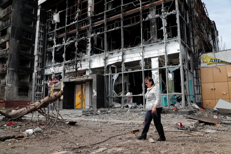 A resident walks by a building destroyed during the Ukraine-Russia war in the southern port city of Mariupol, Ukraine, April 25, 2022.
