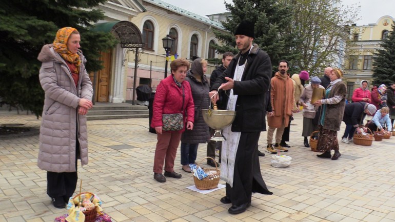 Olha Liforenko, center, a music professor from Kiev, receives blessing near Saint Michael's Monastery [Mansur Mirovalev/Al Jazeera]