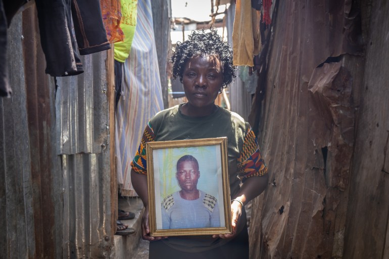 A photo of Benna Buluma standing outside her home in Mathare, holding a photo of Victor.