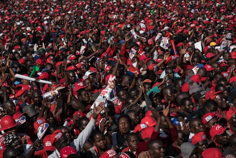 A photo of a sea of people wearing red and holding red signs.