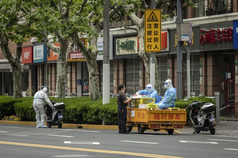 Workers in personal protective equipment (PPE) sit on a rickshaw converted into a mobile COVID-19 testing station during a lockdown in Shanghai, China