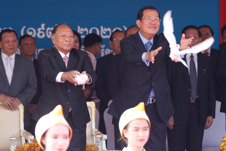 Hun Sen, in a blue suit, releases a white dove into the sky during a parade to mark Cambodia's liberation from the Khmer Rouge