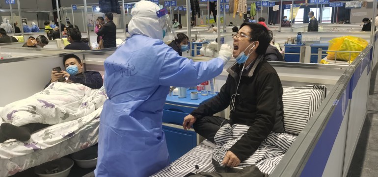 A patient at a temporary hospital in Shanghai gets a covid test from a hazmat suited medic