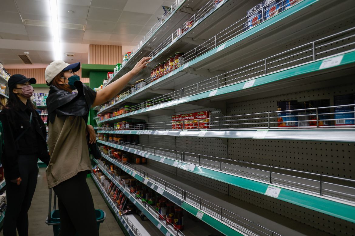 A woman reaches out for pasta sauce at a supermarket in Beijing
