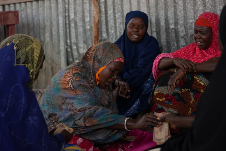 Laylah Tawane and members of her ayuuto group, sit and distribute money from the pot in the camp for displaced people in Mogadishu, Somalia