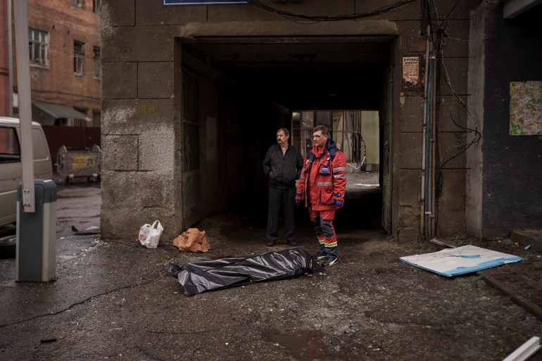 O corpo de uma mulher morta em um bombardeio russo está em uma calçada no centro de Kharkiv, Ucrânia, domingo, 17 de abril de 2022.