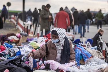 An African woman tries to find some clothes for her as refugees from many different countries - from Africa, Middle East and India - mostly students of Ukrainian universities are seen at the Medyka pedestrian border crossing fleeing the conflict in Ukraine