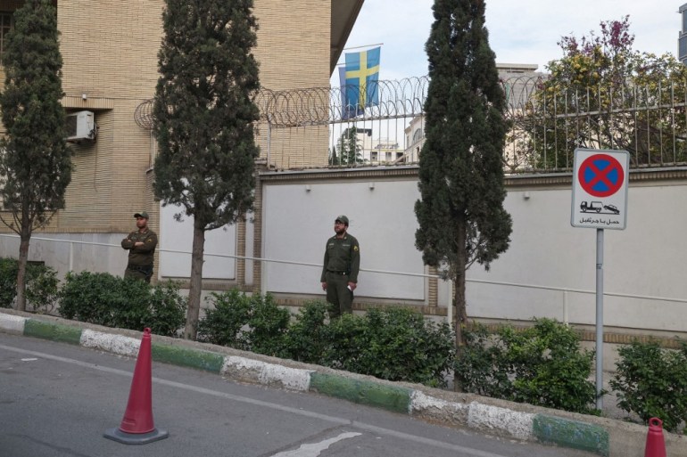 Members of Iranian security forces stand guard in front of the embassy of Sweden in Tehran.