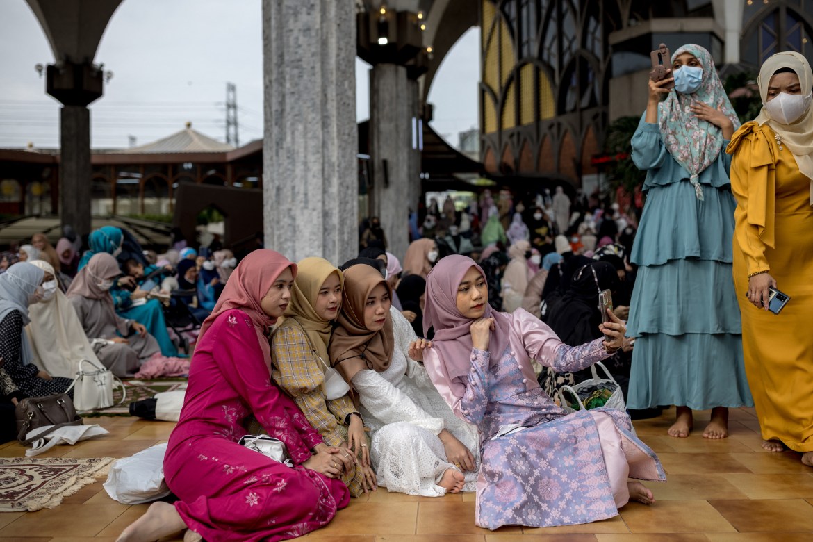 Young women take pictures following morning prayers at The Foundation of the Islamic Centre of Thailand mosque during Eid al-Fitr celebrations, marking the end of the Muslim holy month of Ramadan, in Bangkok