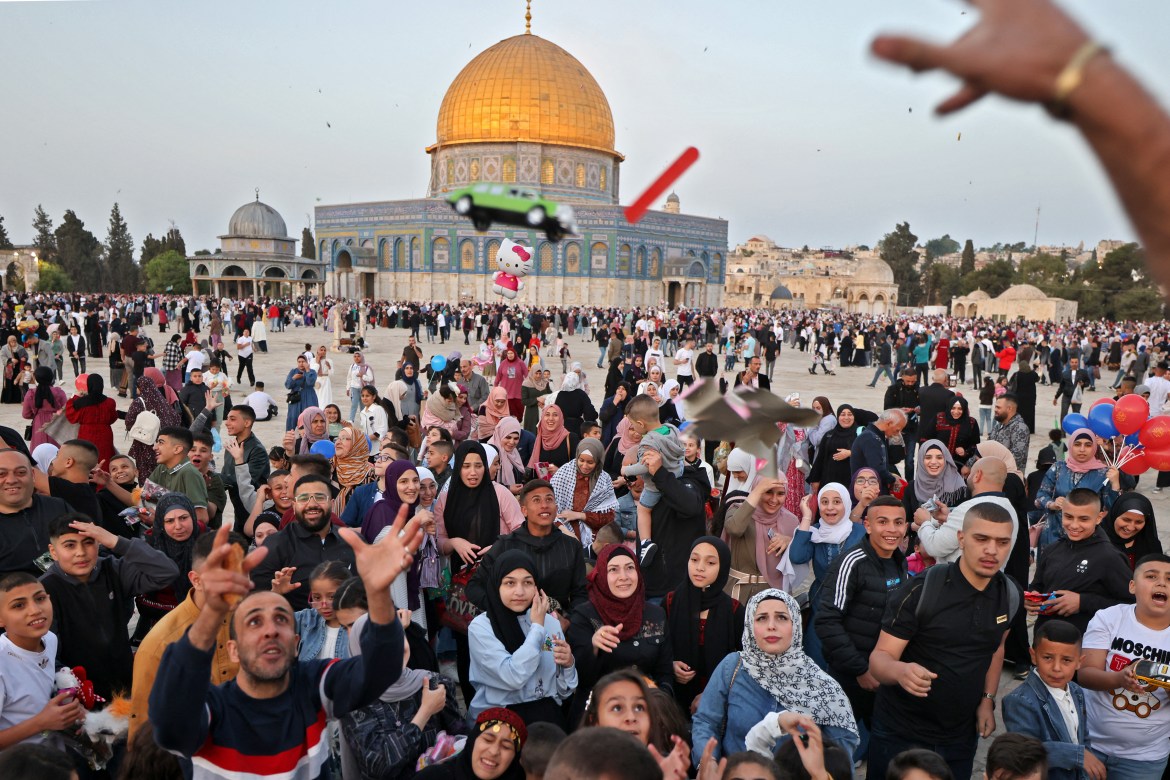 Muslims receive gifts in front of the Dome of the Rock mosque after the morning Eid al-Fitr prayer, which marks the end of the holy fasting month of Ramadan, at the Al-Aqsa mosques compound in Old Jerusalem