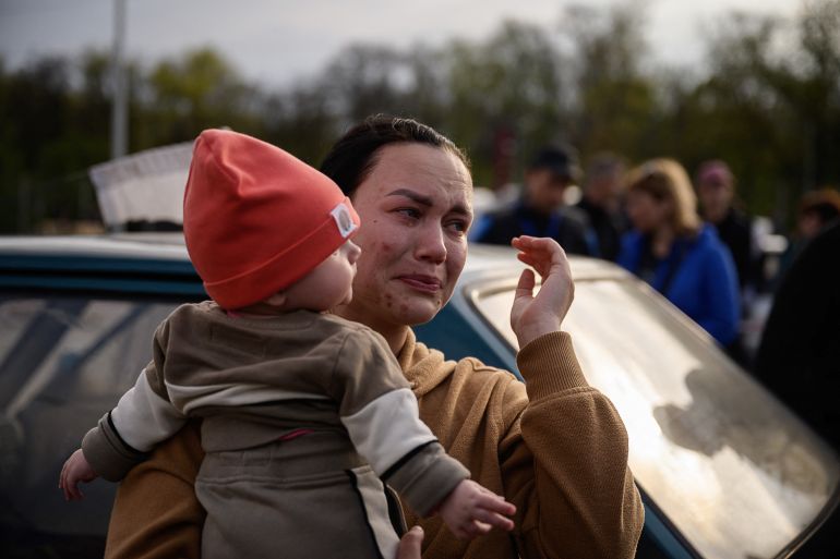 A woman reacts as she holds a child after arriving from a Russian-occupied territory at a registration and processing area for internally displaced people in Zaporizhzhia.