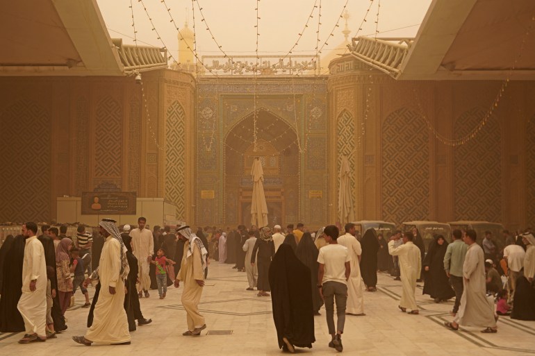 Iraqis visit the Imam Ali shrine during a sandstorm.