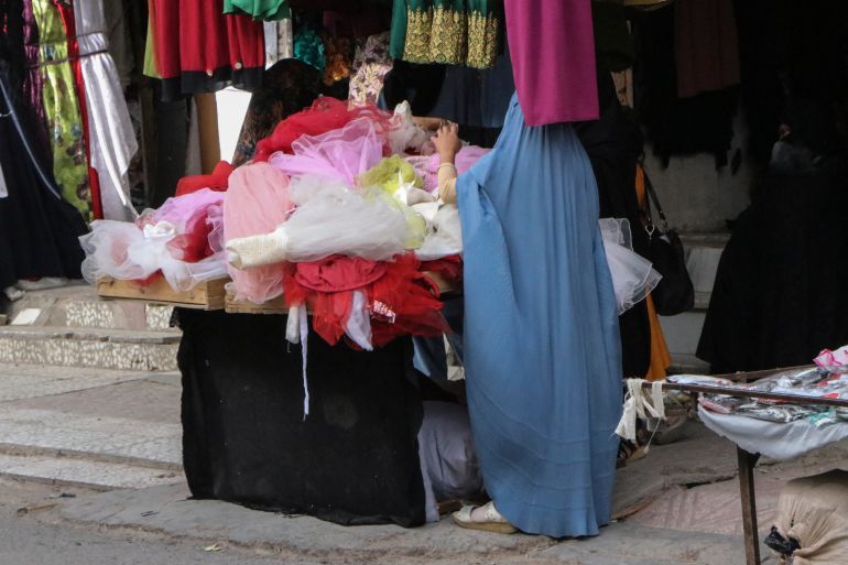 A burqa-clad woman browses through children garments at a shop in Herat on May 7, 2022.