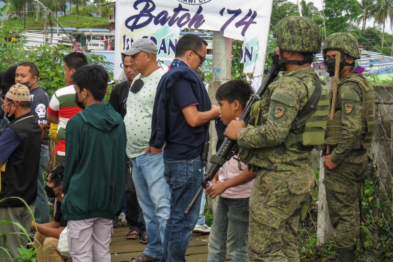 Military personnel stand guard outside a polling precinct during the Philippine presidential election