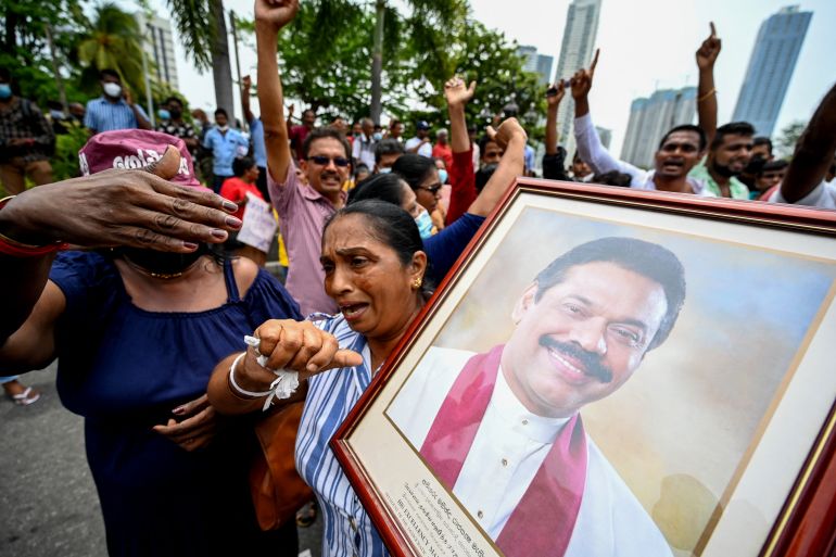 A woman loyal to Rajapaksa carries his portrait during protests outside his official residence