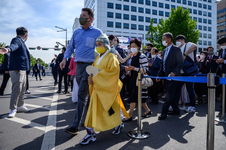 Geleneksel sarı elbiseli bir adam ve oğlu Seul'deki açılış törenine geliyor