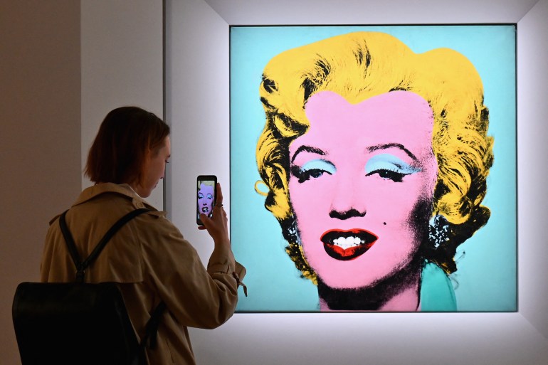 a woman takes a photo of Andy Warhol's 'Shot Sage Blue Marilyn' during Christie's 20th and 21st Century Art press preview at Christie's New York