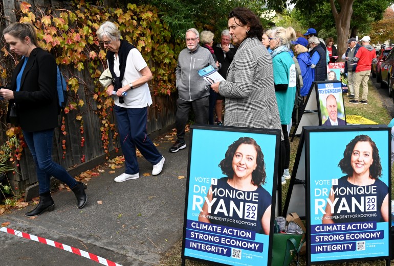 Independent candidate Monique Ryan (C) speaks with a voter on the street outside at a pre-polling centre in Melbourne
