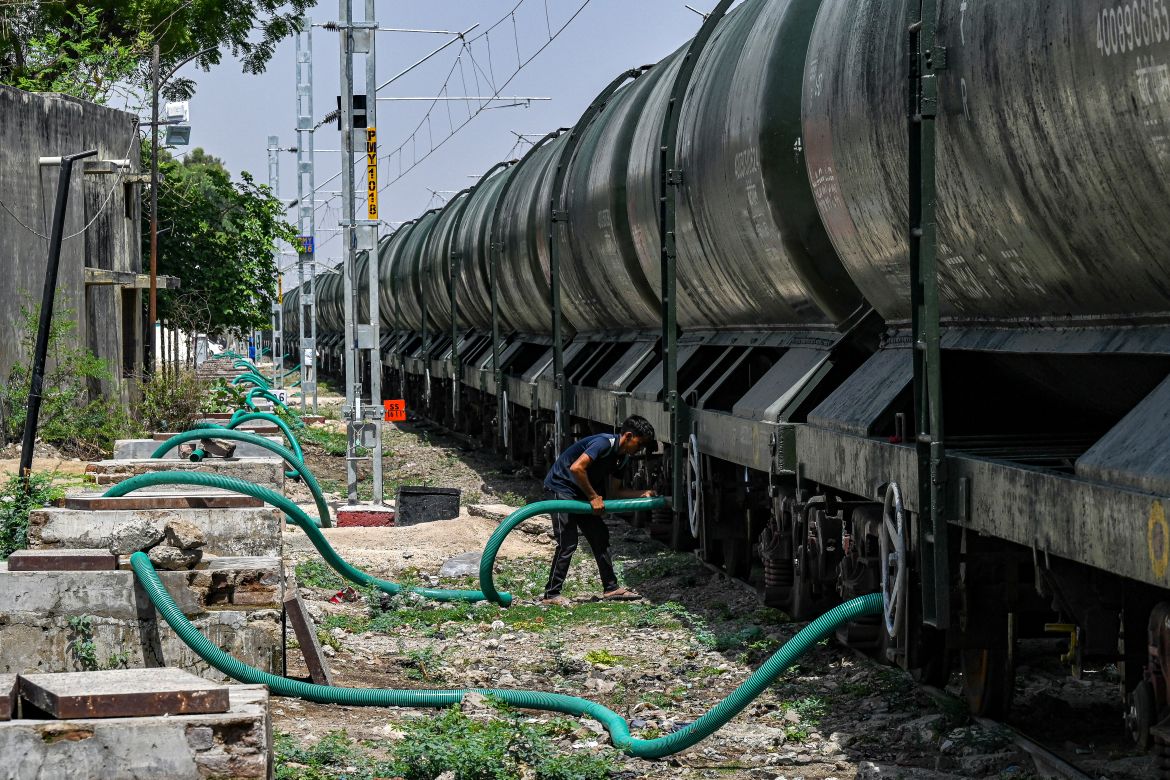 A man fixing a pipe on a tanker to store water in the underground tanks being supplied by a special train on a hot summer day in Pali