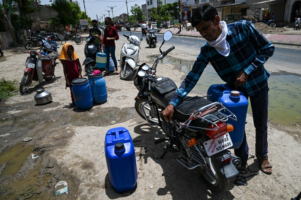 People waiting to refill their containers with tap water supplied by the government on a hot summer day in Pali.