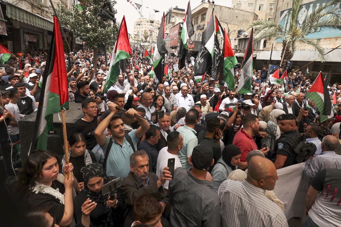 Palestinians wave national flags as they march in a rally marking the 74th anniversary of the "Nakba" or "catastrophe"