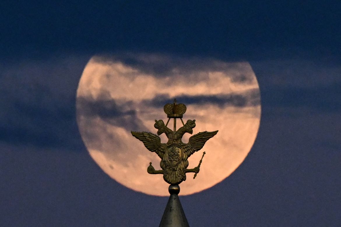 The full moon also known as Flower blood moon is pictured behind the two-headed eagle, the national symbol of Russia atop a building on Red Square in downtown Moscow