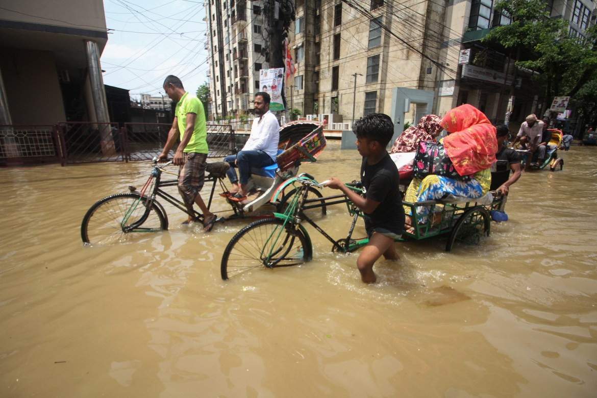 Rickshaw pullers transport customers along a flooded street following heavy rainfalls in Sylhet