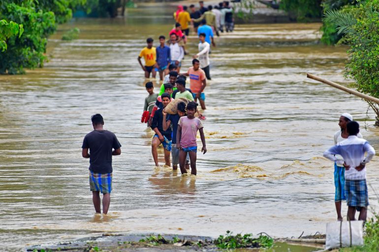 Villagers wade through a flooded road after heavy rains in Hojai district of India's Assam
