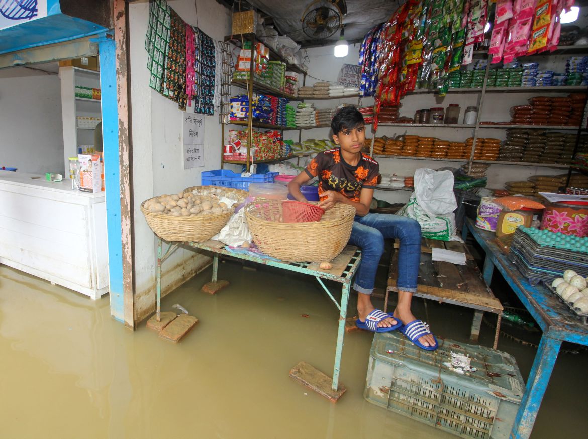 A boy sits at a shop along a flooded street following heavy rains in Sylhet