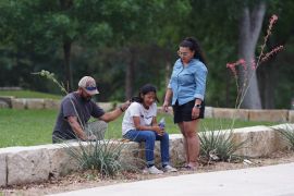 A girl cries, comforted by two adults, outside the Willie de Leon Civic Center where grief counseling will be offered in Uvalde